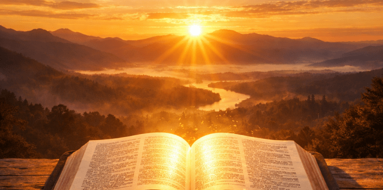 Open book on wooden surface with sunrise over river and mountains